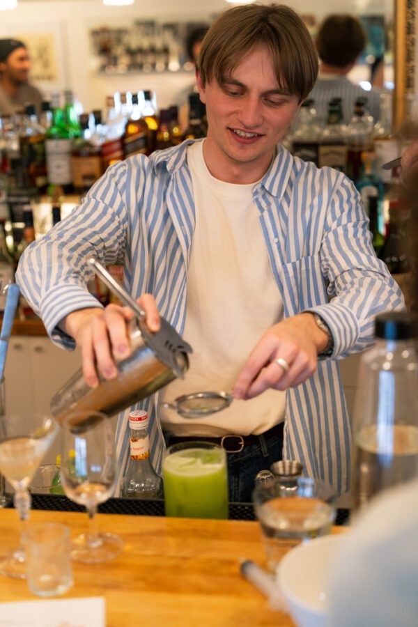 Ein Teilnehmer seiht einen Cocktail durch ein feines Sieb ab